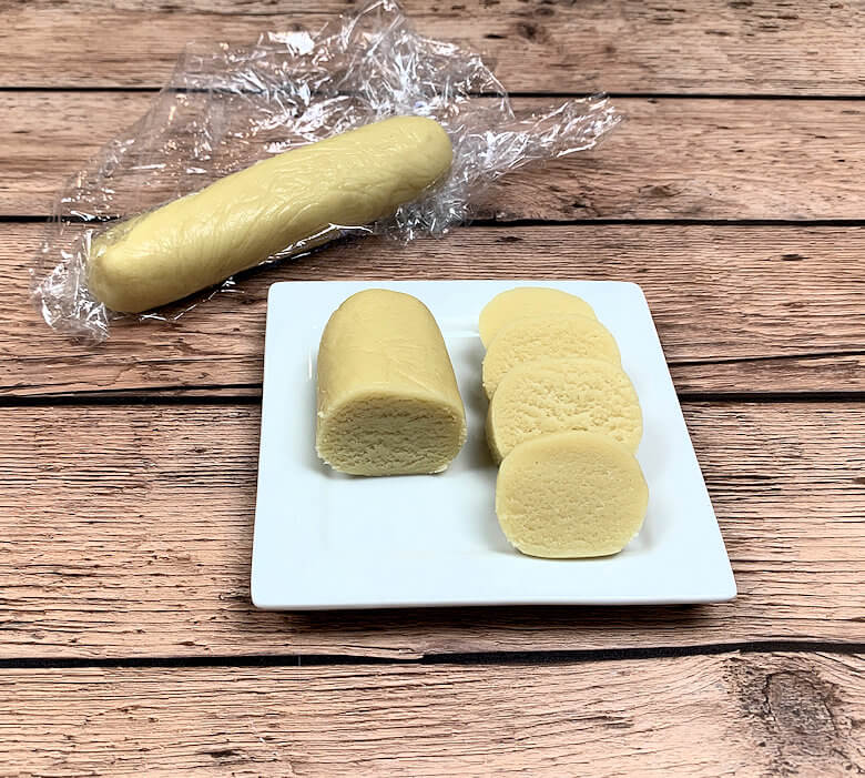 Almond paste cut on a dish and rolled in plastic wrap.