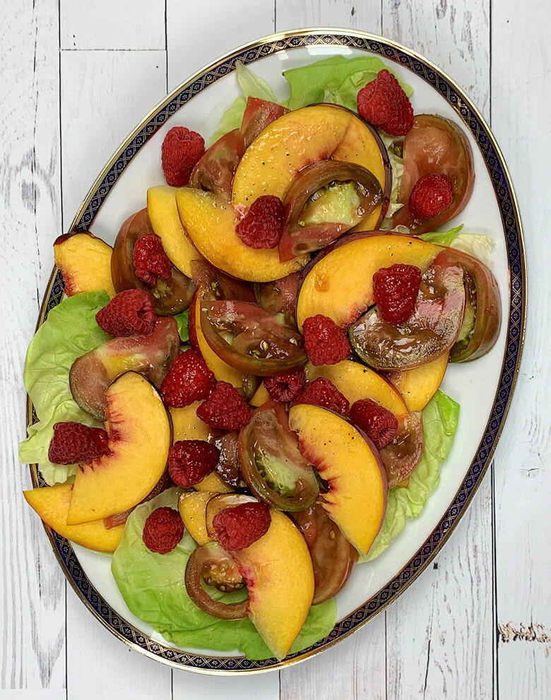 Oval dish with butter lettuce salad with peaches and tomatoes