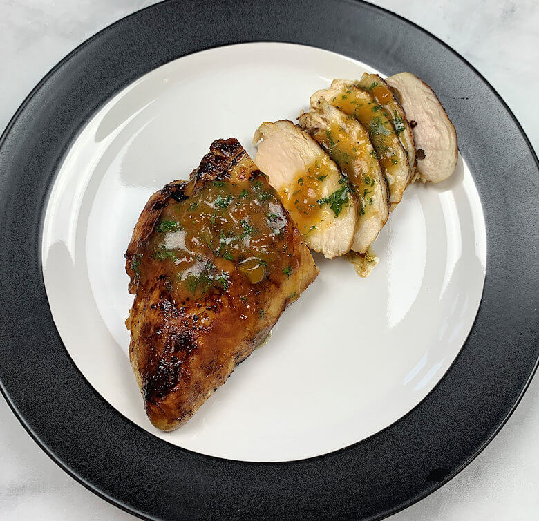 Plate with partly sliced chicken breast with Apricot Mint Sauce