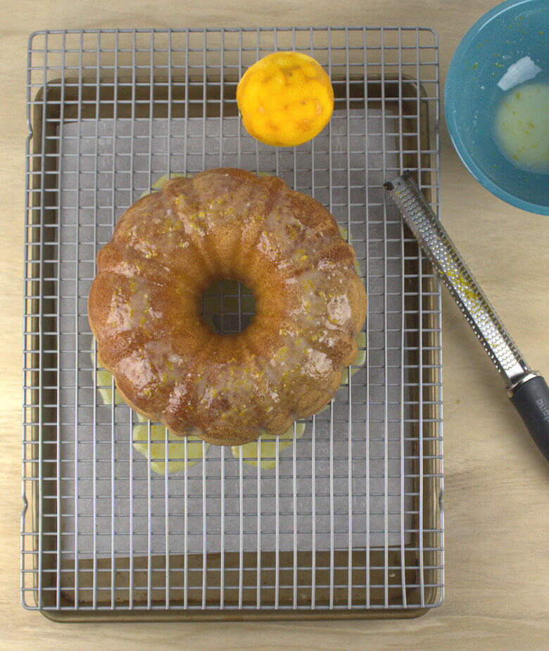 Picture of Light Orange Buttermilk Bundt Cake with glaze ripping on baking sheet