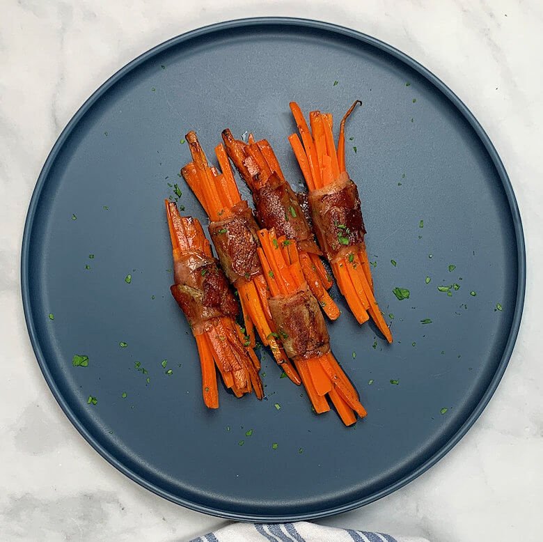 Blue plate with prosciutto wrapped carrot sticks