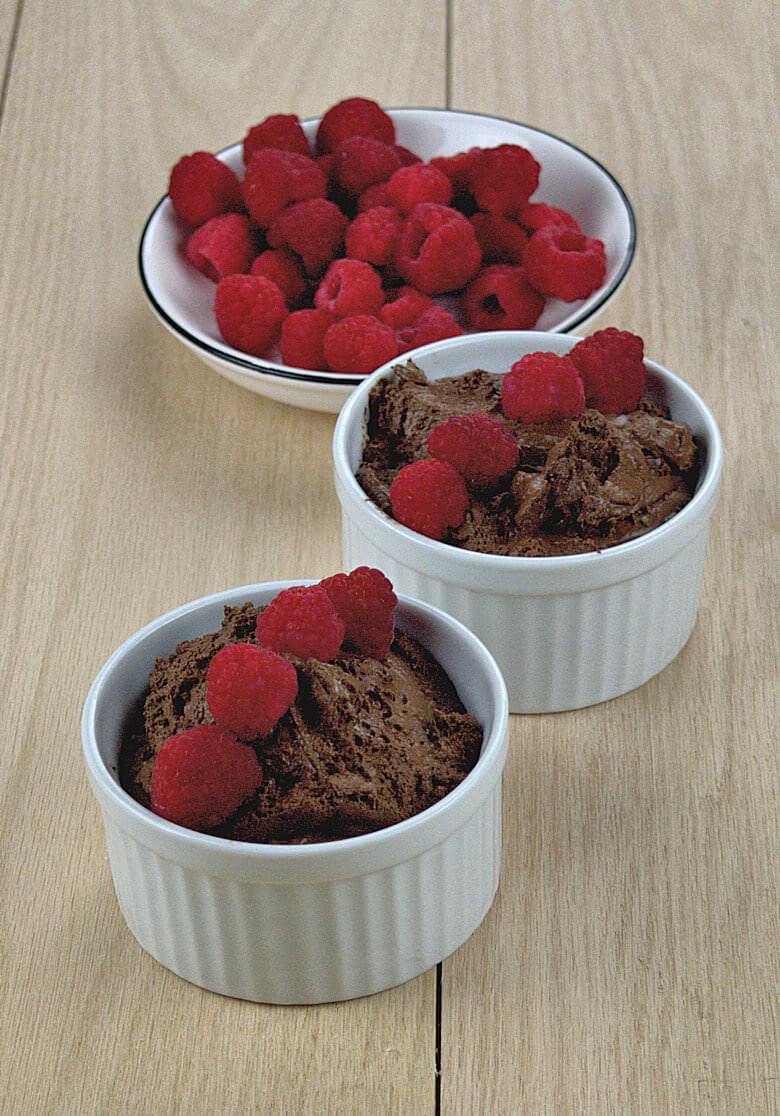 Picture of two bowls of chocolate mousse, decorated with fresh raspberries